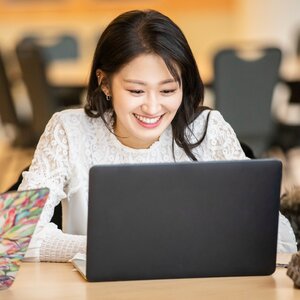 Woman in a white dress smiles while using a laptop computer.
