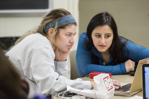Two female undergraduate students work together on a computer.