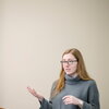 Female student with red hair and grey sweater presents at a KIN undergraduate course