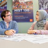Academic advisor for the history department works with a female undergraduate student on her class schedule in his office.