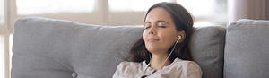 RIO program woman with headphones on couch