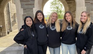 college women in matching black sweatshirts in an academic hall