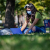 student in mask studying in grass on the quad