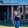 a woman student in a mask is playing frisbee outside her residence hall